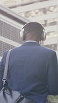 Businessman, dance and walking in city with headphones, streaming music or morning commute for job. Back, person outdoor and rhythm in urban town with audio tech, online radio and travel to work.