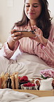 Phone, photography and woman with breakfast in bed for room service, hospitality or hotel meal. Mobile, picture or person in bedroom with food on tray for social media post, relax or smile in morning