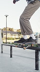 Legs, person and jump with skateboard for grind on rail in city for trick, training and sports. Skateboarder, sneakers and leap for stunt at skatepark, exercise and hobby with balance outdoor