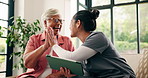 High five, tablet and old woman with caregiver on couch, health assessment results and celebrate wellness. Positive feedback, elderly care and happy people with tech in home, laugh or checkup success