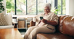 Coffee, phone and senior woman in home for relax, morning news or thinking in retirement on sofa. Tea, smile and elderly person with mobile for reflection, online communication or reading article