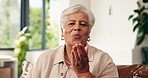 Face, blowing kiss and old woman at home, smile and flirting with fun, laughing and funny. Apartment, pensioner and senior person on couch, happiness and hand gesture for romance, humor and kindness