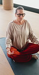 Old woman, lotus and meditation with yoga on gym floor, breathing exercise and eyes closed at club. Elderly person, mudra and holistic fitness with mindfulness, glasses and retirement at studio
