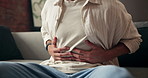 Man, hands and stomach ache with discomfort on sofa for pain, diarrhea or indigestion in home. Male person, tummy bug or sore belly with cramp for gastrointestinal reflux or constipation in house