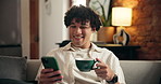 Home, coffee and happy man on sofa, smartphone for social media and message to contact. Apartment, espresso and person on couch, relax and cellphone for online reading and website for entertainment