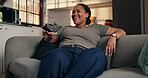 Laughing, woman and watching tv with remote, lounge and streaming comedy with subscription in house. Happy, black person and relax with controller for entertainment, funny movie and humor in home
