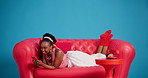 Funny, cellphone and black woman on sofa in studio, meme or message to contact. Laugh, online humor or African person on couch, smartphone for social media, comedy video or comfort on blue background