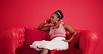 Phone call, speaking and black woman on couch in studio, funny story and listening for conversation. Gossip update, talking and happy person laugh with mobile on sofa, connectivity and red background