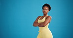 Black woman, face and fitness with confidence in studio for workout on a blue background. Portrait, female person or active model with arms crossed, strength or power for health and wellness on space