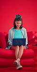 Studio, woman and happy with laptop on couch, online and editing video for website and mockup space. Red background, influencer and person with tech for content creation, laugh or social media upload