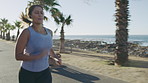 Woman, fitness and running with earphones on ocean coast, sidewalk or promenade for workout. Active, female person or runner with sprint, race or exercise for cardio training, health or wellness