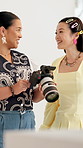 Women, talk and photographer with camera at studio with clothes, choice or happy for creative process. People, production and discussion with picture, smile and feedback for fashion at media agency