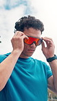 Fitness, runner and man with sunglasses, outdoor and running for wellness on road, cardio or active. Healthy, athlete and person with endurance for exercise, serious and training routine in city