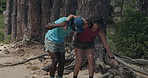 People, hiking and help with accident in forest for sprain, muscle tension or pain on outdoor trail. Interracial couple, carrying or partner with sore leg or joint inflammation for trekking injury
