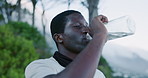 Runner, man and drinking water on mountain with exercise break, electrolytes or hydration for fitness. Active, black person and beverage in nature with thirst, wellness and workout rest for recovery.