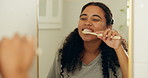 Brushing teeth, mirror and woman in home, oral hygiene and morning routine for self care. Dental health, reflection or person in bathroom, toothpaste or cleaning mouth for wellness or remove bacteria