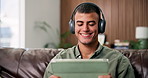 Headphones, tablet and man on sofa for relax, music video or watch movie on internet in living room. Audio, tech and happy person in home for streaming service with show, film or listen to podcast