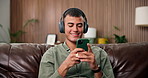 Headphones, mobile and man in home for relax, music video or radio on internet in living room. Audio, phone and happy person on sofa for streaming service with sound, song or listen to podcast