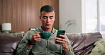 Coffee, phone and relax with man on sofa in living room of home for rest or social media browsing. App, break and text message with person blowing warm drink in apartment for me time scrolling