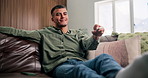 Happy, remote and man on sofa watching tv in home on weekend for movie, show or series in living room. Relax, subscription and male person streaming film on channel with television in apartment.