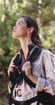 Woman, hiking and adventure in forest with bag, tourist sightseeing and vacation activity for wellness. Bokeh, person trekking or journey outdoor with backpack for nature exploration, travel or trip.
