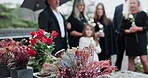 Flowers, family and funeral by tomb at cemetery, graveyard or outdoor for farewell or burial. Child, people and group together for grief, death and respect with bouquet for eulogy, mourning and loss