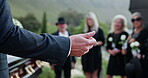 Funeral, hands or pastor with speech at graveyard, memorial service or tribute for religious practice. Speaking, Christianity or people with priest for farewell ceremony, burial or remembrance prayer