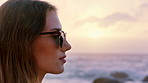 Sunset, thinking and woman with sunglasses at beach, remember sad memory and introspection for holiday. Ocean, summer break and calm person with disappointment for vacation, shades or past reflection