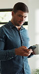 Man, coffee and reading with phone in home for games, browsing website and texting. Male person, typing and beverage with mobile for streaming movies, social media and notification for message update