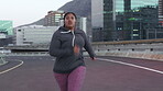 Earphones, exercise and running with woman on bridge in city for cardio workout or fitness routine. Challenge, music and streaming with runner on street outdoor for health benefits or training