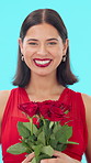 Woman, face and red roses in studio with smile for valentines day, gift and pride on blue background. Girl, excited and floral bouquet for present, portrait or confidence with celebration in Portugal