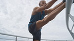 Man, fitness and stretching legs in city with earphones, exercise start or preparation for training. Below, person or runner warm up on bridge with wellness, begin or getting ready for cardio workout