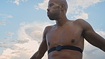 Man, runner and outdoor with strap for heart rate, monitor and low angle with break for fitness. African person, wearable tech and rest with breathing, thinking and shirtless for exercise in summer