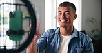 Phone, ring light and influencer with conversation for live stream, content creation and social media in home. Man, streamer and gen z person with tech for broadcast, chat and online interaction