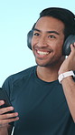 Dance, athlete and man with headphones in studio, laughing and song selection with smartphone or web. Blue background, streaming and happy person with mobile for audio subscription, fitness and music