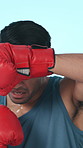 Boxing, tired and face of man in studio with gloves for training, exercise and intense competition. Fitness, practice and person with sweat for challenge, sports match and fight on blue background
