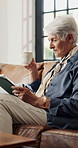 Coffee, tablet and elderly woman in living room for reading news, relax or email in retirement home. Warm beverage, technology and old person on sofa for online article, ebook or rest on weekend