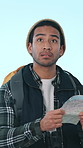 Hiking, confused and man with map in studio for navigation, direction and location for tourism. Travel, lost and person with paper guide on adventure, backpacking and journey on blue background