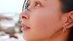Woman, relax and thinking on beach with wind, peace and wondering for inspiration on vacation trip. Person, reflection and tranquility outdoor by ocean with breeze, wellness and memory on holiday.