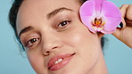 Happy woman, orchid and face for skincare in studio with flower, beauty or purple petals on background. Girl, smile and blossom for sustainable cosmetics, confident or spring for portrait in Spain