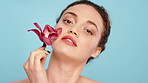 Beauty, flower and wellness with face of woman in studio for cosmetics or dermatology. Natural, orchid plant and vegan skincare with model person on blue background satisfaction or sustainability