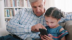 Phone, game and grandfather with child on sofa in home for learning, development or growth together. Scrolling, technology and senior man with girl kid on cellphone for online gaming in living room.