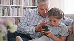 Senior man, child and phone at house on social media, watching movies and bonding. Grandfather, talking and kid with mobile for streaming cartoon, video games and website subscription in living room