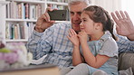 Grandpa, phone and wave with girl on sofa in home living room for bonding, love or visit. App, blowing kiss and video call  of senior man with happy granddaughter in apartment for communication