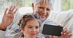 Grandma, girl and phone with video call, wave goodbye and bonding together for weekend in living room. Happy, old woman and grandchild in home with tech, contact and greeting for virtual connection.