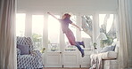 Superhero, child and jumping on couch in home, laughing and boy with energy in living room and game. Kid, happiness and fly on air in lounge, playing and freedom on weekend, fun or activity in house