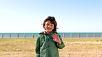 Outdoor, face and boy with wave for greeting, travel destination and winter holiday for weekend trip. Beach, space and happy child with hello gesture for video call, nature and portrait for vacation