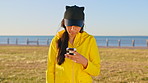 Teenager, scroll and holiday by beach with phone, social media update or notification for text message. Face, gen z girl and smile by ocean with tech, stop and finish typing online post for vacation.