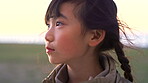 Outdoor, thinking and child with smile for holiday, remember funny memory and positive mindset for trip. Wind, laughing and asian girl with reflection for vacation, sightseeing and view location