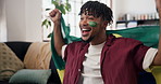 Victory, cheer and football fan in house with flag, goal excitement or celebration in sports tournament. Supporter, watching soccer or latino man with game, score lead or winning shout in Brazil.